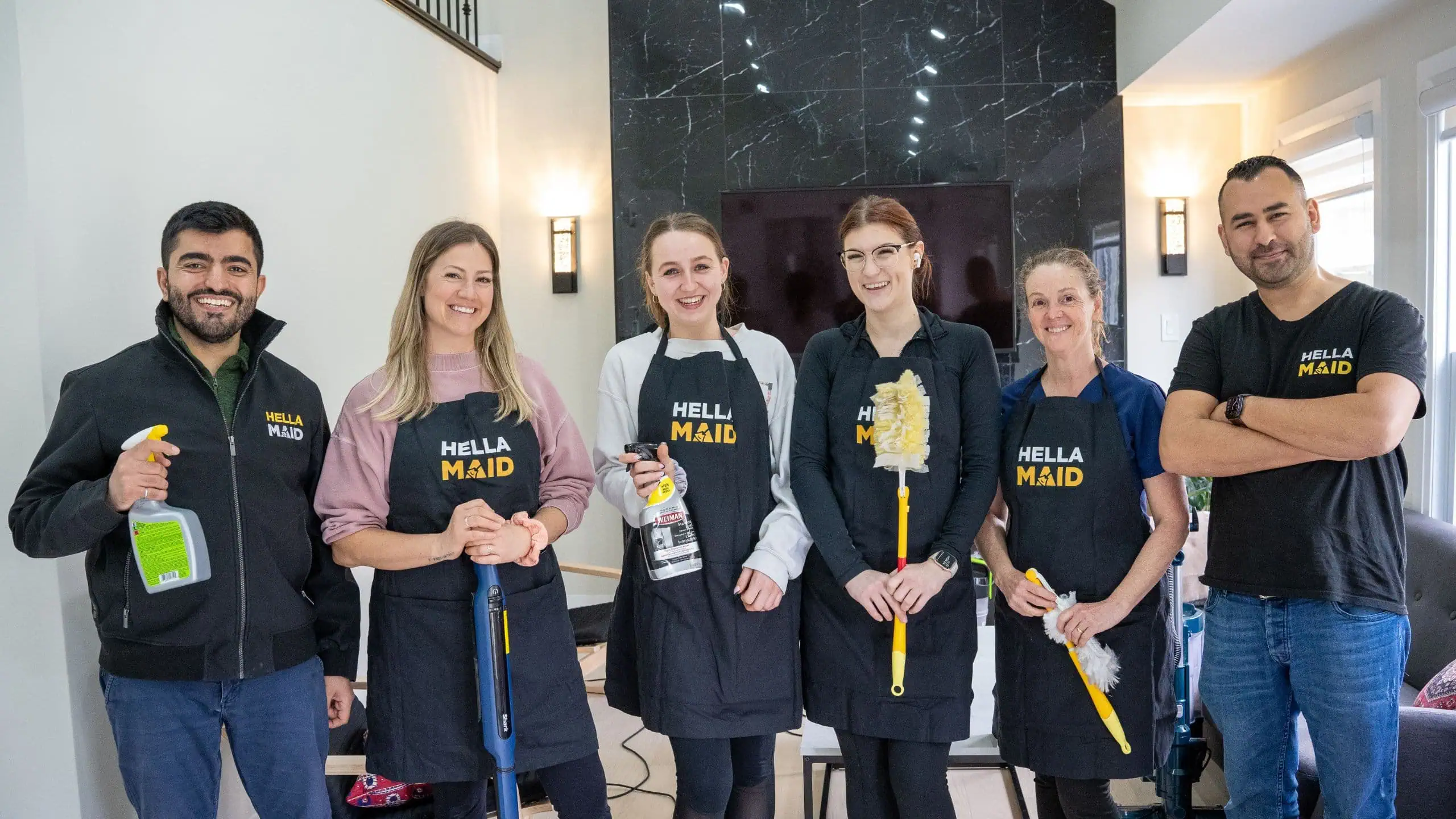 a group of women wearing aprons and holding cleaning supplies