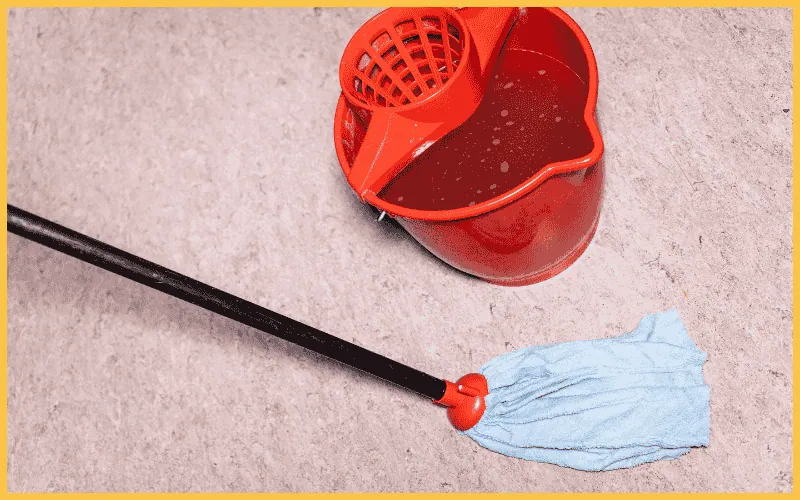 mop washes linoleum floor near red bucket