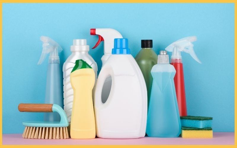 A colorful array of cleaning supplies, including bottles, sprays, and sponges, arranged against a bright blue background.