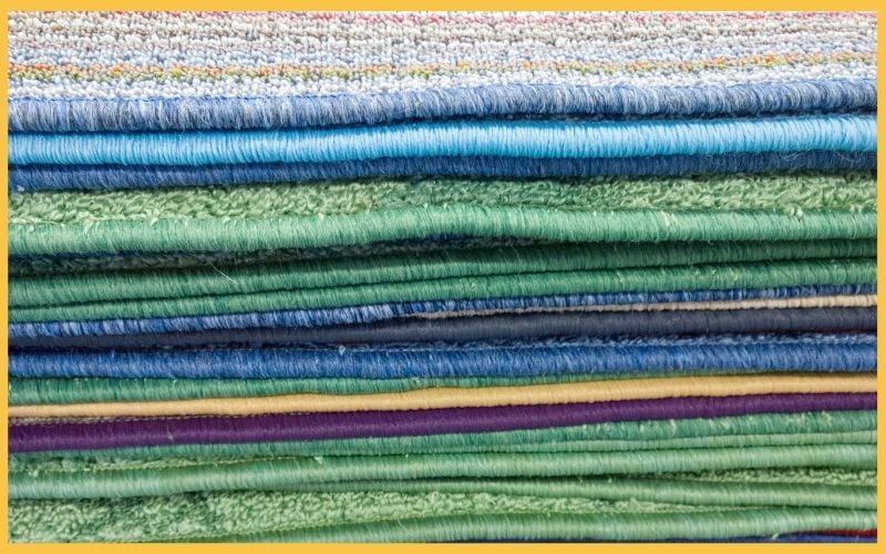 A vibrant stack of neatly folded fabric swatches in various shades of blue, green, and purple, showcasing different textures and patterns.